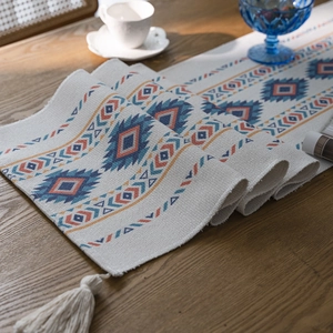 Bohemian table runner with geometric diamond pattern and white tassels on wood table