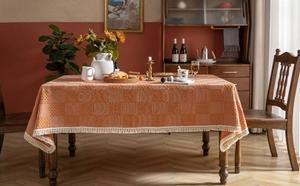 Detail der orange-weißen Jacquard-Tischdecke mit eleganten weißen Quastenkanten und Textur