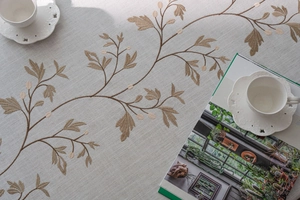 Detail of grey cotton linen tablecloth showing intricate brown floral branch embroidery