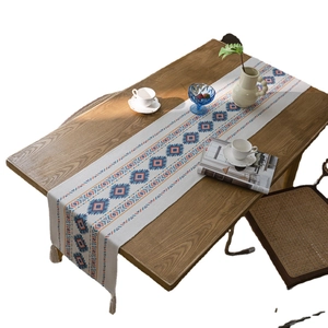 Bohemian table runner with geometric diamond pattern and tassels on wood table