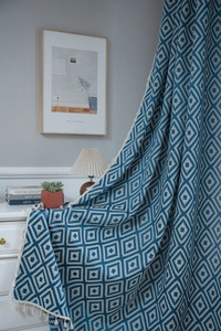 Detail of navy and beige geometric woven throw blanket with decorative cotton tassels