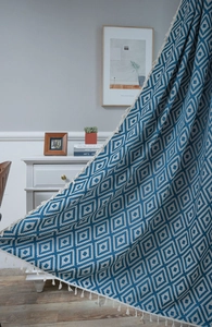 Close-up of blue and white geometric jacquard fabric with elegant woven fringe tassels