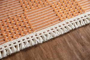 Detailaufnahme der Jacquard-Tischdecke mit geometrischem Muster und weißen Fransen