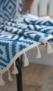 Close-up of bohemian navy blue and beige knitted throw blanket with geometric diamond patterns