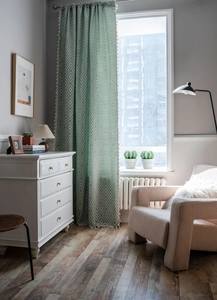 Detail showing mint green geometric pattern curtains with elegant white tassel edges