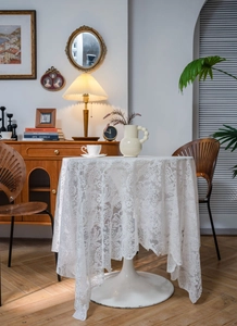 Close-up of vintage white lace tablecloth with detailed floral embroidery and wavy edges