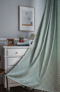 Detail of mint green geometric weave curtain featuring dense white tassel edges and texture