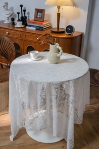 Detail of white lace tablecloth with floral patterns and delicate bead decorations
