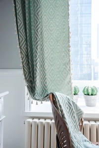 Close-up of mint green and cream geometric woven fabric with tassel fringe detail