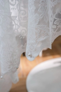 Close-up of elegant white floral embroidery lace with delicate pearl beaded scalloped edges
