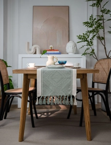 Detail of Nordic jacquard table runner with green geometric patterns and soft tassels