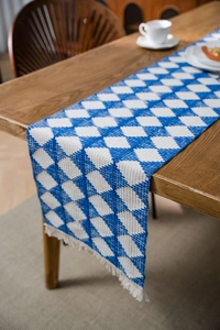 Detailed view of blue and white geometric diamond woven table runner with white tassels