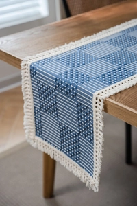 Detailed view of Nordic geometric jacquard table runner with fringe on dark wood table