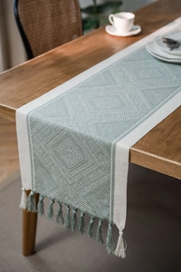Close-up of Nordic geometric jacquard table runner with decorative tassels on wood