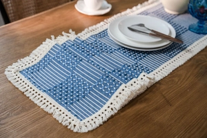 Detail of blue and white geometric woven table runner with decorative cotton tassels
