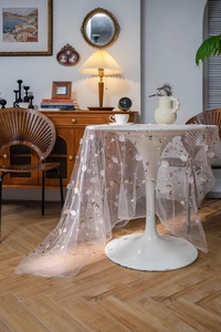 Detailed embroidery of pink flowers on a delicate mesh lace tablecloth for home decor