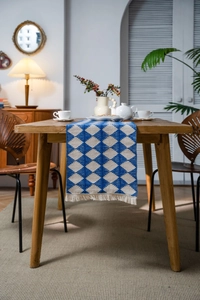 Detail of blue and white geometric diamond weave table runner with white cotton tassels
