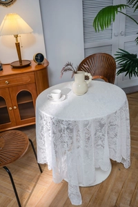 Detailed close-up of white lace tablecloth with floral crochet patterns and delicate beads