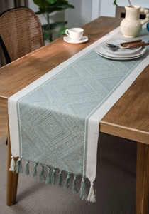 Detail of sage green and beige geometric jacquard table runner with woven tassels