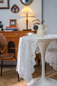 Close-up of white lace tablecloth with floral crochet patterns and delicate pearl bead trim