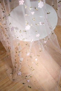 Detail of pink semi-transparent lace mesh with delicate 3D floral embroidery on white table