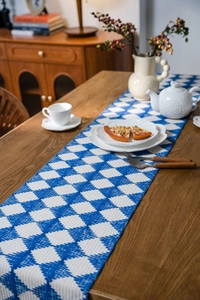Detail of blue and white geometric woven table runner with tassels on a dark wooden table
