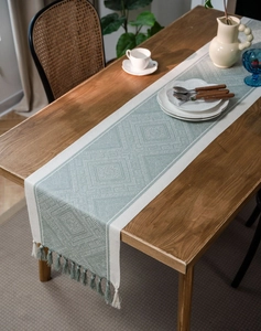 Close-up of Nordic geometric jacquard table runner with sage green tassels and woven texture
