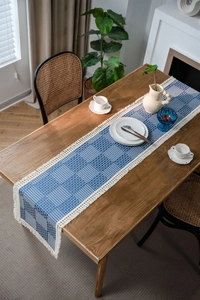 Detailed view of woven blue and white checkered table runner with elegant white tassels