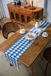 Detailed texture of blue and white geometric woven table runner with decorative tassels