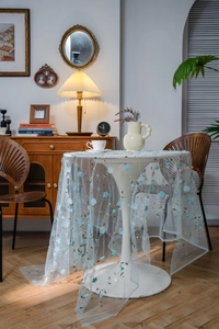 Detail of light blue mesh tablecloth with delicate floral embroidery in French retro style