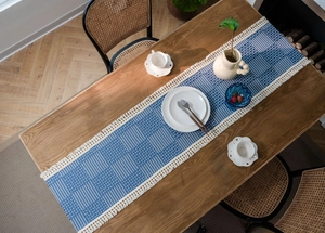 Close-up of geometric jacquard table runner with blue and white stripes and white tassels