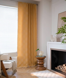 Detail of yellow waffle weave curtain with delicate fringes in a cozy room setting