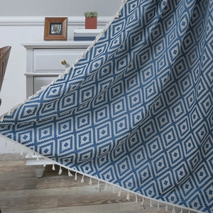 Blue and white geometric diamond woven blanket with decorative white fringe trim