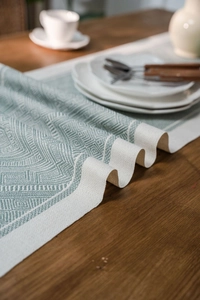 Detail of mint green geometric jacquard table runner on a dark wood dining table