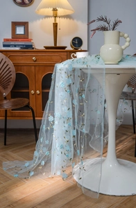 Close-up of light blue mesh lace with 3D floral appliques and gold leaf embroidery details