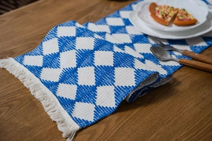 Macro detail of cotton woven table runner with blue geometric pattern and tassels
