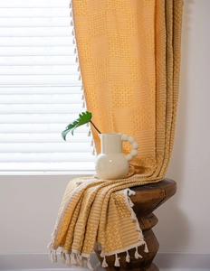 Detail showing mustard yellow striped curtain with white geometric texture and fringe