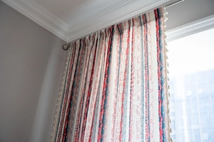 Close-up of geometric striped cotton linen curtain with decorative white tassels and textures