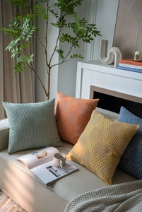 Close-up of modern jacquard textured pillow covers in green, orange, and blue on sofa