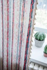 Detailed view of bohemian geometric patterned cotton linen curtain with cream tassels