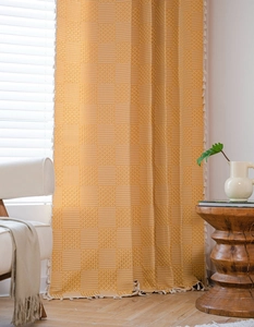 Detail of bohemian mustard yellow woven curtain with geometric patterns and fringe tassels