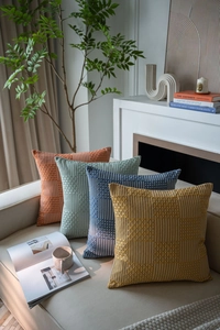 Detail of jacquard woven pillow covers with geometric texture on a beige sofa