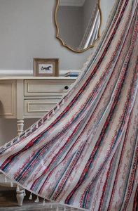Close-up of bohemian red and blue geometric pattern curtain with white cotton tassels