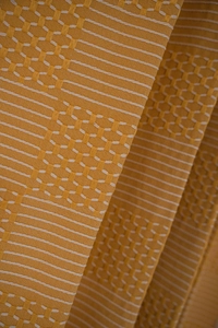 Detail of mustard yellow textured curtain fabric with woven honeycomb and stripe patterns