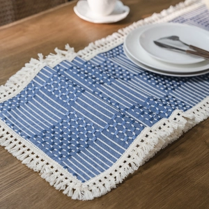 Nordic blue and white geometric woven table runner with decorative tassels on wood table