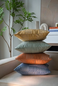 Close-up of stacked jacquard pillow covers with thick knitted texture on a beige sofa