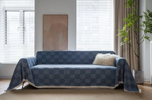 Close-up of geometric pattern on navy sofa throw blanket with decorative white fringes