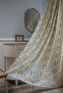 Detailed close-up of floral print linen curtains featuring elegant white fringe tassels