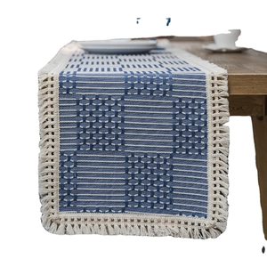 Blue and white geometric jacquard table runner with fringe on a wooden table