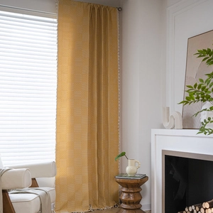Mustard yellow curtains with geometric pattern, tassel trim, and natural cotton-linen texture